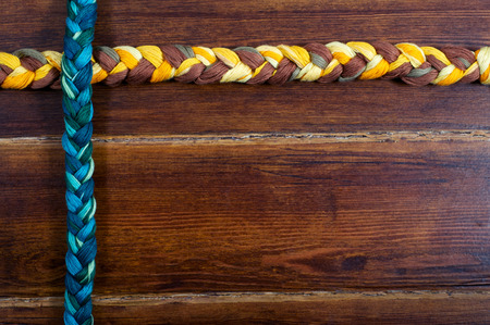 Green and yellow braids over brown wooden badkgroundの写真素材