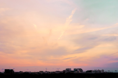 Orange and purple pastel sky scape at dusk with city's silhouette and cloudの写真素材