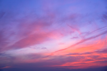 Dark blue sky with red coral streaks shining throughout clouds. Cloud art. Dark tone pictureの写真素材