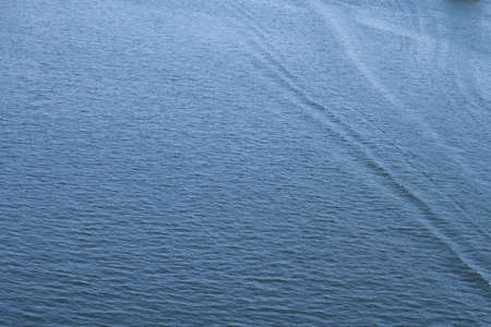 slight ripples on the water surface with diverging waves, background photoの写真素材