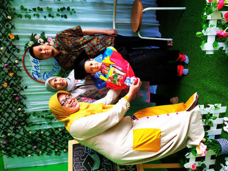 Kindergarten with graduation gown and family is holding the beautiful craft flower bouquet in his hands for the ceremony.のeditorial素材