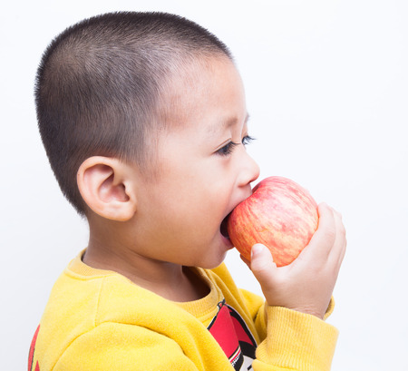 Portrait of a happy little boy with red apples, isolated over whiteの写真素材