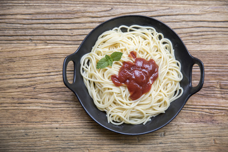 pasta with tomato sauce and basil leaves at wooden deskの写真素材