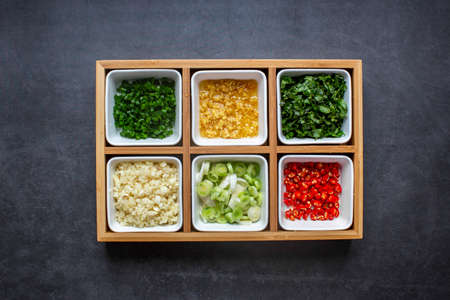 Chopped Fresh Coriander leaves and Green onion and Ginger and Chili pepper and garlic in white plate on black background. top view.の写真素材