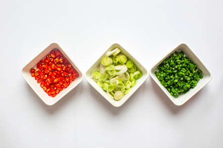 Chopped Green onion and Chili pepper and garlic in white plate on white background. top view.の写真素材
