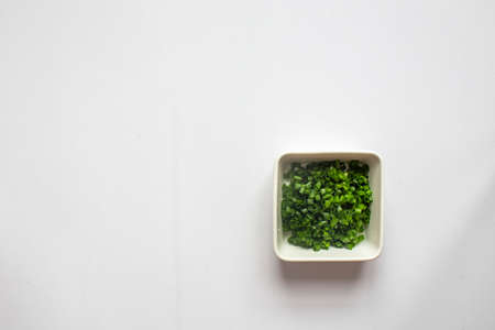 Chopped green onions in white plate on white background. top viewの写真素材