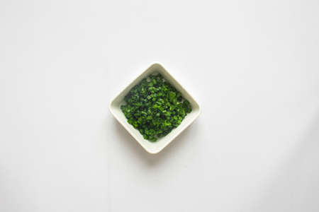 Chopped green onions in white plate on white background. top viewの写真素材
