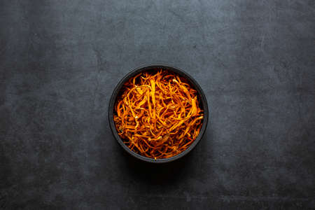 Dried cordyceps militaris mushroom in bowl on dark grey background. Cordyceps flowerの写真素材