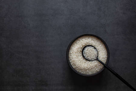 Rice in bowl and spoon on dark grey background.の写真素材