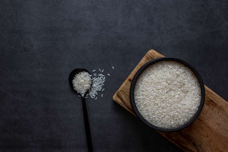 Rice in bowl and spoon on dark grey background.の写真素材