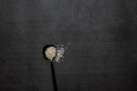 Rice in bowl and spoon on dark grey background.の写真素材