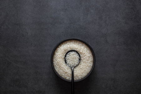 Rice in bowl and spoon on dark grey background.の写真素材