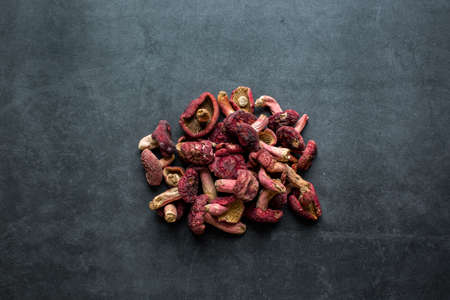 The bright red mushroom is a good nourishing food. Dried red mushroom in bowl on dark grey background.の写真素材