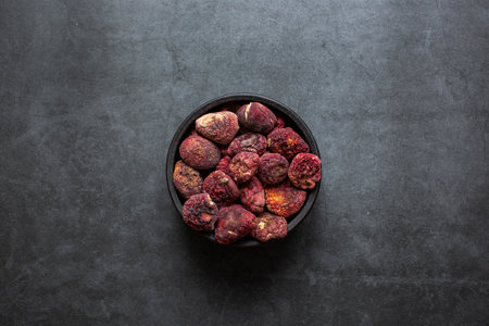 The bright red mushroom is a good nourishing food. Dried red mushroom in bowl on dark grey background.の写真素材