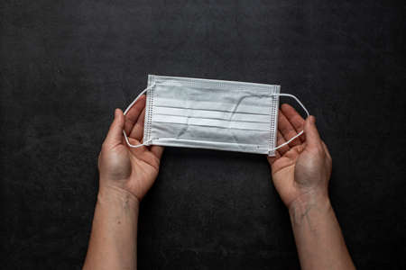 Surgical mask with rubber ear straps. Typical 3-ply surgical mask to cover the mouth and nose. Procedure mask from bacteria. Protection concept.の写真素材