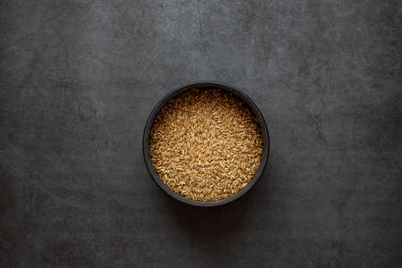 Oats rice in bowl on dark grey background.の写真素材