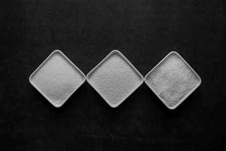 sugar and salt and MSG in white dish on black background.の写真素材