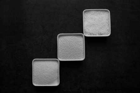 sugar and salt and MSG in white dish on black background.の写真素材