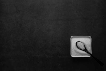 sugar in white dish on black background.の写真素材