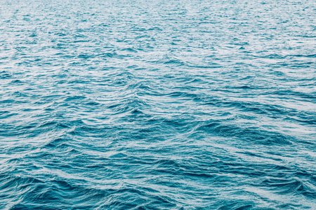 This is a detailed closeup image of a serene body of water showing gentle waves lapping at the surface, reflecting various shades of blue and tranquilityの写真素材