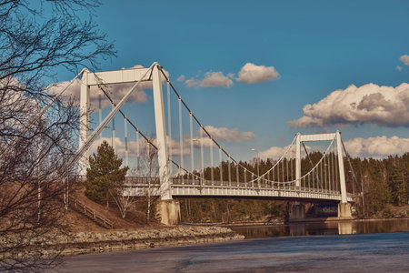 A Beautiful Suspension Bridge Gracefully Spanning Over A Tranquil River Landscape Scene