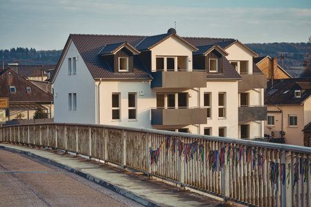 A white house with a brown roof is situated next to a bridgeの写真素材