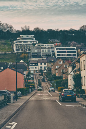 A car is steadily driving down a narrow street in a quaint small townの写真素材