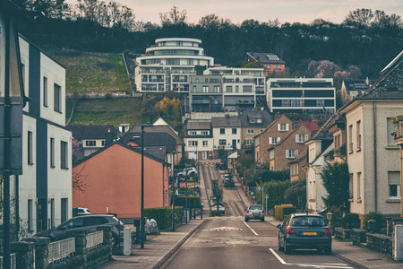 A car is steadily driving down a narrow street in a quaint small townの写真素材