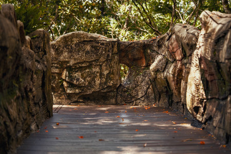 A peaceful and tranquil wooden walkway gracefully weaves through vibrant lush greenery and rugged rock formationsの写真素材