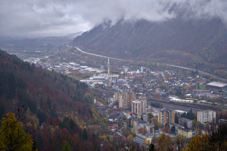 quiet town nestled among colorful mountains, majestic valley under overcast sky with peaceful riverの写真素材