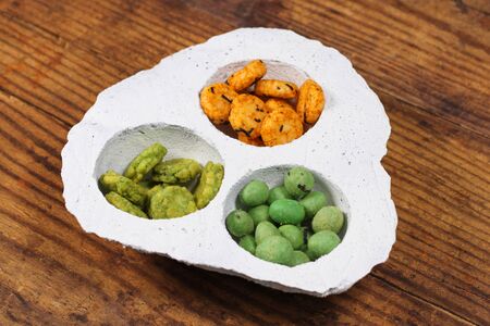 Wasabi rice snacks in a white bowl on wood backgroundの写真素材