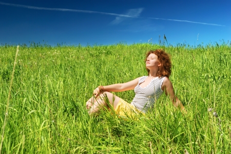 Young girl sitting on green fieldの写真素材