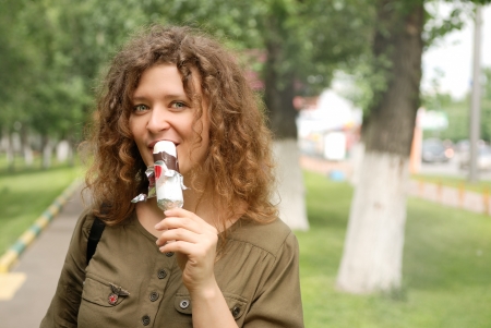 young woman eating ice-cream at streetの写真素材