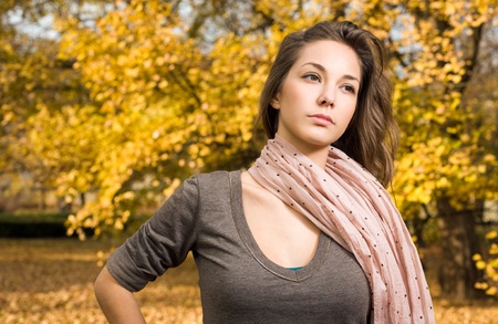 Gorgeous young brunette strolling in autumn park.の写真素材
