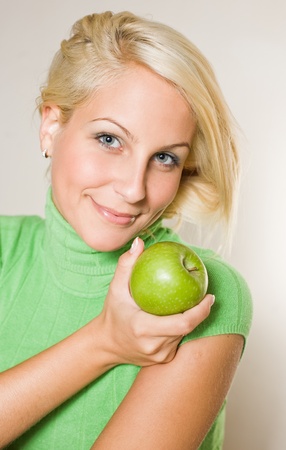 Portrait of smiling fresh young blond girl holfing green apple.の写真素材