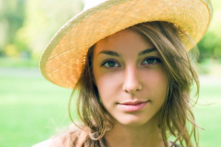 Beautiful young spring brunette outdoors in nature wearing a straw hat.の写真素材