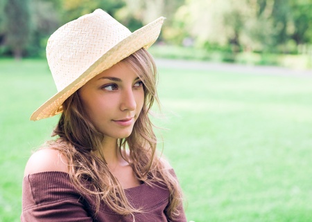 Beautiful young spring brunette outdoors in nature wearing a straw hat.の写真素材
