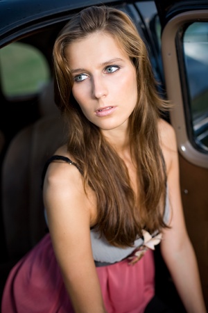 Gorgeous young brunette posing outdoors with beautiful black vintage car.の写真素材