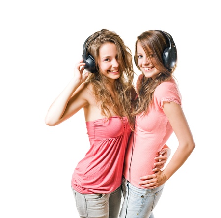Share your tune, two gorgeous brunette teens having fun with headphnes, isolated on white.の写真素材