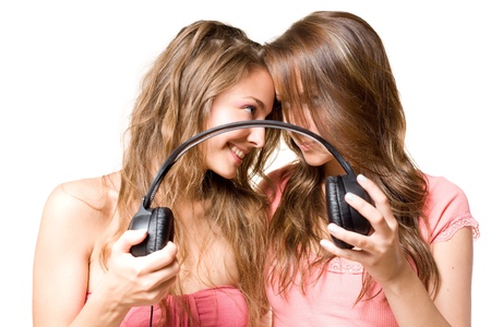 Share your music, two beautiful young brunette girls fighting oiver headphones, isolated on white background.の写真素材