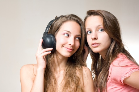 Two beautiful young brunettes sharin their music playing with their headphones.の写真素材