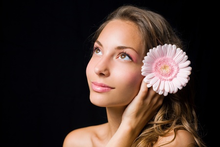 Gorgeous smiling young brunette holding pink flower.の写真素材