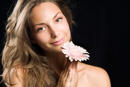 Gorgeous smiling young brunette holding pink flower.の写真素材