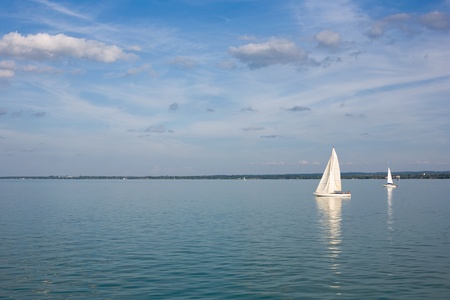 Sailing away on bluw waters with strip of land behind.の写真素材