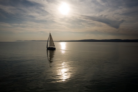 Small boat sailing into the sunset.の写真素材