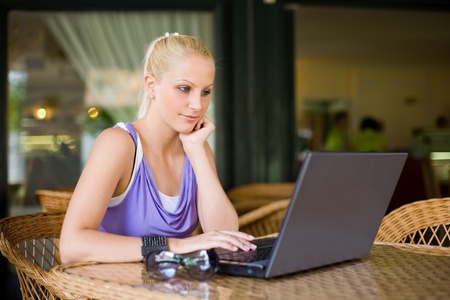 Beautiful young blonde using her laptop at the coffee shop.の写真素材
