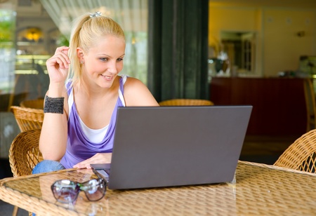 Portrait ofd beautiful young blonde woman being happy about findings through her laptopの写真素材