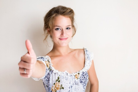 Portrait of a cheerful fashionable young blond woman showing thumbs up.の写真素材