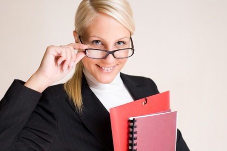 Portrait of beautiful friendly smiling businesswoman peeking over her glasses.の写真素材