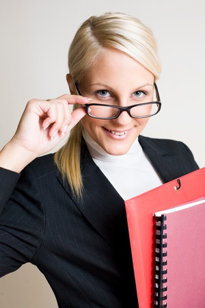 Portrait of beautiful friendly smiling businesswoman peeking over her glasses.の写真素材